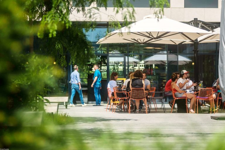 Letní posezení skupiny lidí na terase podniku u Blumental Offices na Náměstí Mateja Korvína